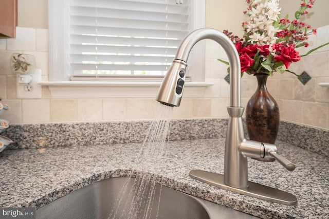 kitchen view of a sink, tasteful backsplash, and light stone counters