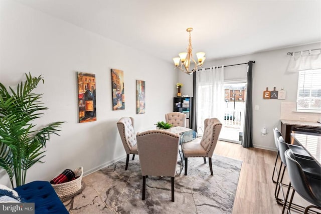 dining room featuring a chandelier, baseboards, and light wood-style floors