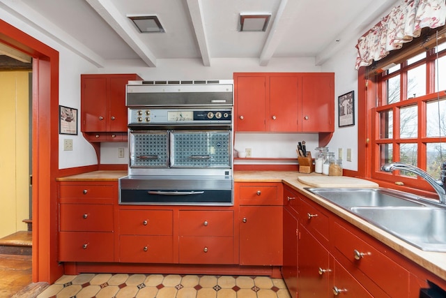 145 Fort Defiance Rd, Fort Defiance, VA 24437 - kitchen featuring wall oven, beamed ceiling, red cabinetry, a sink, and light countertops