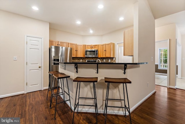 10614 Rhoads Dr, Fredericksburg, VA 22407 - kitchen featuring appliances with stainless steel finishes, a breakfast bar area, dark countertops, backsplash, and recessed lighting