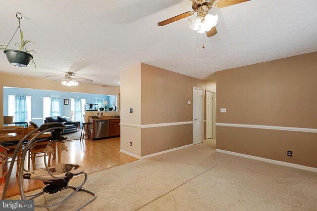 living area featuring ceiling fan, light colored carpet, and baseboards