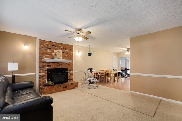 living area with ceiling fan, carpet flooring, a fireplace, a textured ceiling, and baseboards