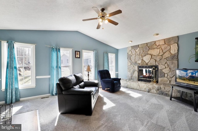 living room featuring carpet floors, vaulted ceiling, a ceiling fan, a fireplace, and a textured ceiling