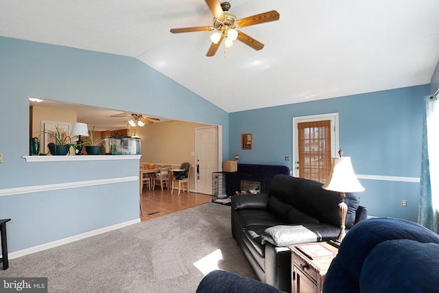 carpeted living area featuring a ceiling fan, vaulted ceiling, and baseboards