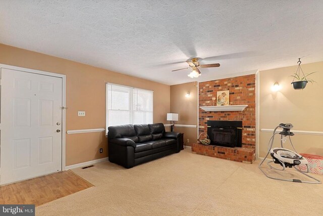 carpeted living area with a ceiling fan, a textured ceiling, baseboards, and a fireplace