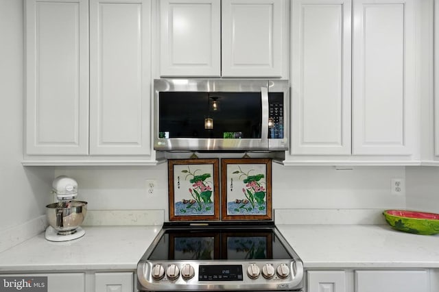 kitchen featuring appliances with stainless steel finishes, white cabinetry, and light stone countertops