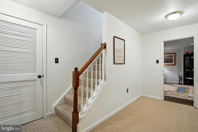 staircase featuring carpet floors and baseboards