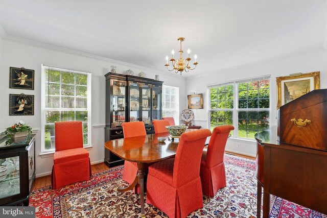 dining space with a chandelier, wood finished floors, crown molding, and baseboards