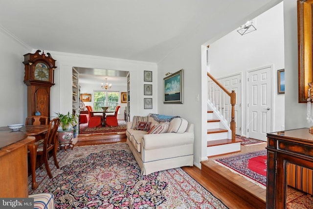 living room with a chandelier, wood finished floors, stairway, and crown molding