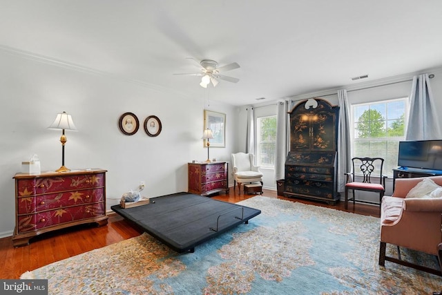 bedroom featuring multiple windows, wood finished floors, ornamental molding, and a ceiling fan