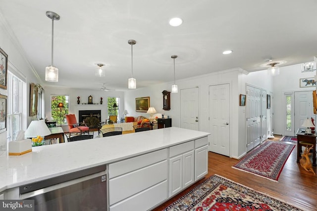 kitchen featuring crown molding, wood finished floors, pendant lighting, white cabinetry, and open floor plan
