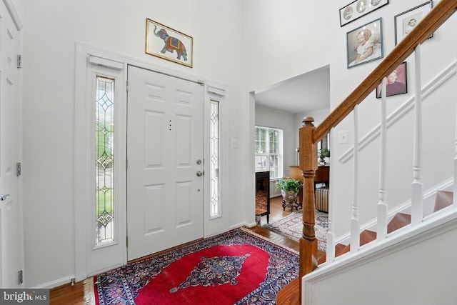 foyer with wood finished floors, baseboards, and a towering ceiling