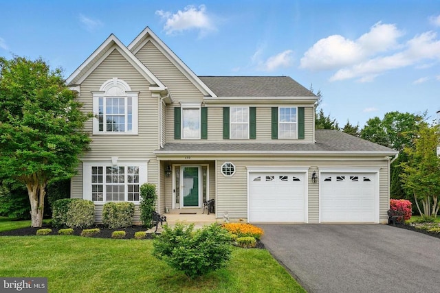 traditional-style home with driveway, a front yard, and a shingled roof