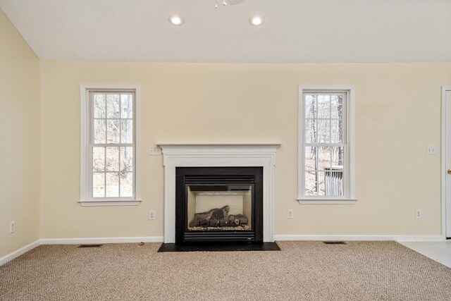 unfurnished living room featuring carpet, baseboards, visible vents, and a wealth of natural light