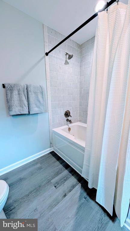 176 Tussing Ln, Rochelle, VA 22738 - bathroom featuring wood finished floors, shower / bath combination with curtain, toilet, and baseboards