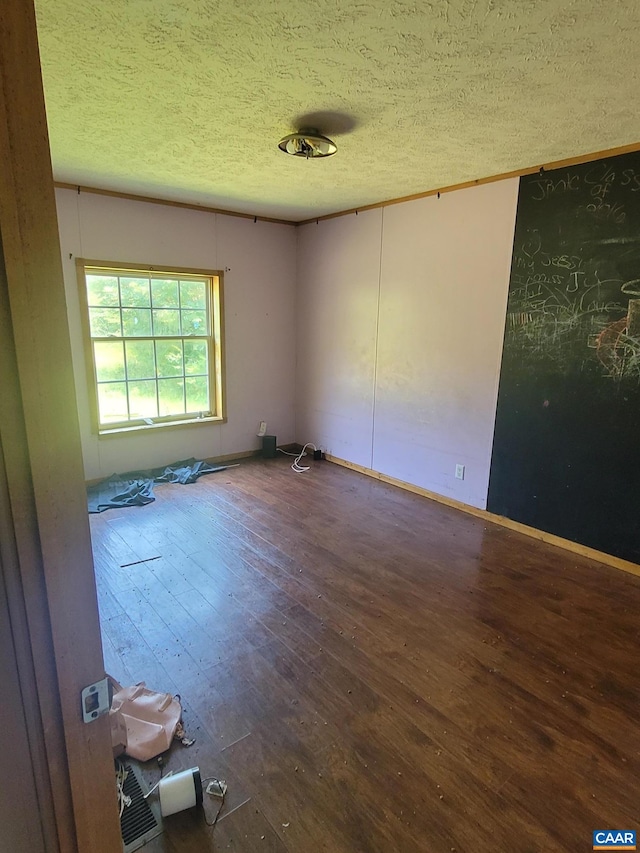 spare room featuring baseboards, a textured ceiling, and hardwood / wood-style flooring