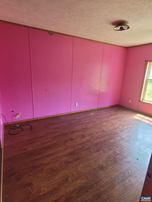 empty room featuring a textured ceiling and wood finished floors