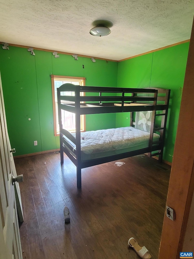 bedroom featuring baseboards, wood-type flooring, and a textured ceiling