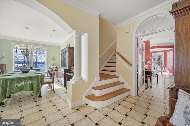 foyer entrance featuring crown molding, stairs, ornate columns, and a chandelier