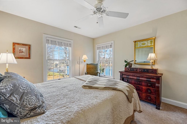 carpeted bedroom with baseboards, a ceiling fan, and visible vents