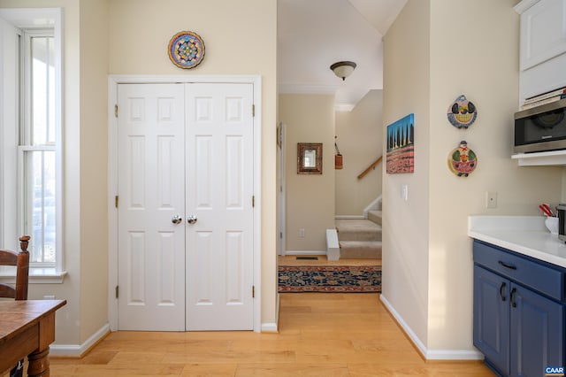 interior space with light countertops, stainless steel microwave, light wood-style flooring, blue cabinets, and baseboards