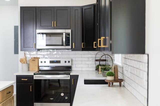 9 Walnut St, Fishersville, VA 22939 - kitchen featuring appliances with stainless steel finishes, light countertops, a sink, decorative backsplash, and dark cabinetry