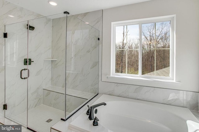 bathroom featuring a bath, healthy amount of natural light, and a marble finish shower