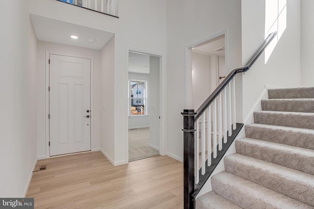 foyer entrance featuring light wood-style flooring, stairway, and baseboards