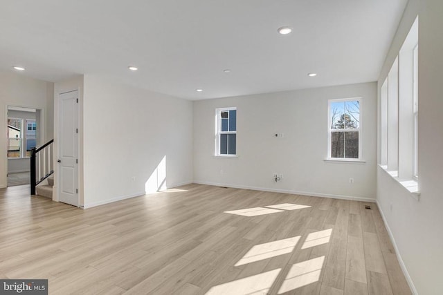 spare room featuring baseboards, light wood-style floors, recessed lighting, and stairs
