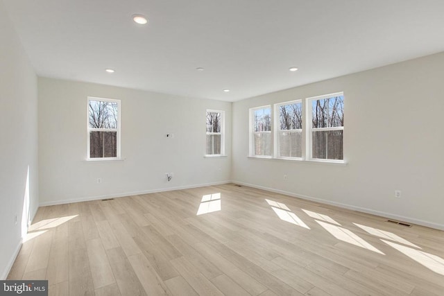 empty room with light wood-type flooring, baseboards, and recessed lighting