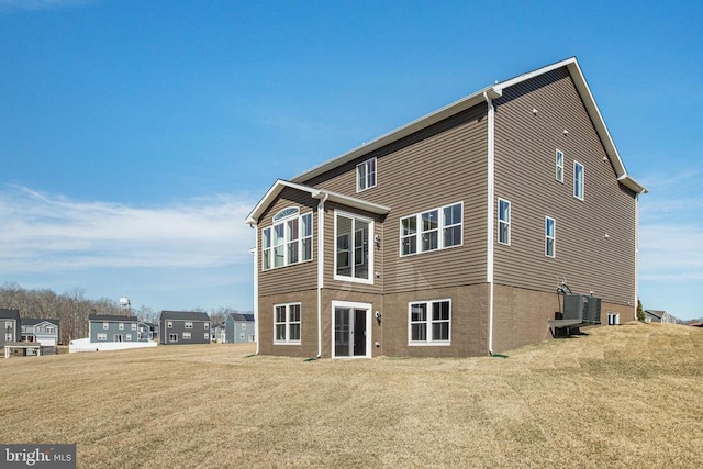 back of property featuring a yard and brick siding