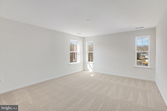 spare room with baseboards and light carpet