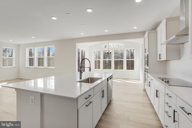 kitchen featuring a sink, wall chimney range hood, appliances with stainless steel finishes, a chandelier, and light countertops