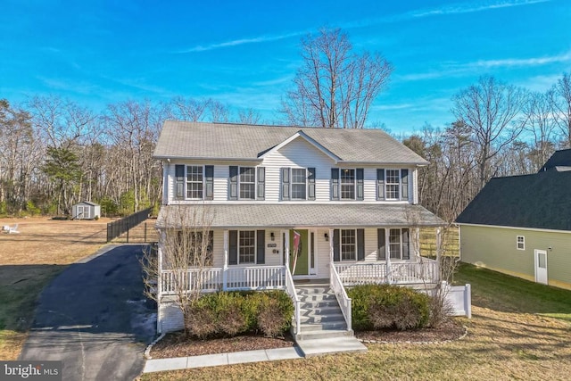 colonial home featuring a front yard, an outbuilding, a shed, and covered porch