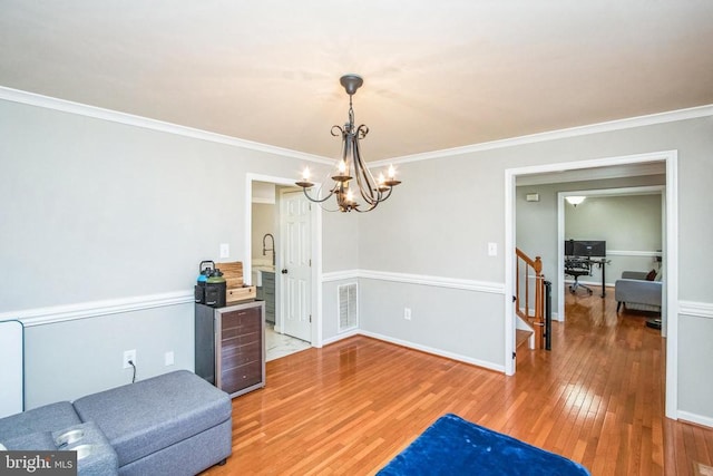 interior space with baseboards, light wood finished floors, an inviting chandelier, visible vents, and crown molding