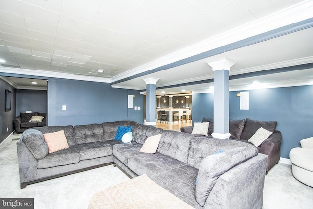living room with crown molding, carpet, baseboards, and ornate columns