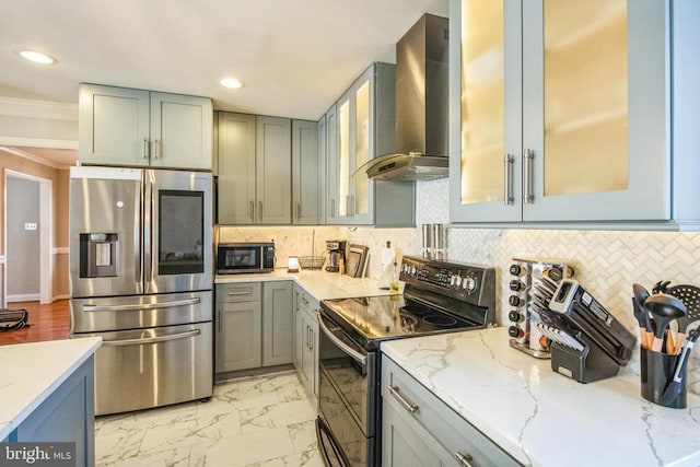 kitchen with light stone countertops, wall chimney range hood, range with two ovens, and stainless steel refrigerator with ice dispenser
