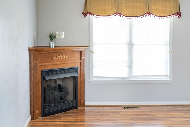 living area featuring wood finished floors, baseboards, and a fireplace