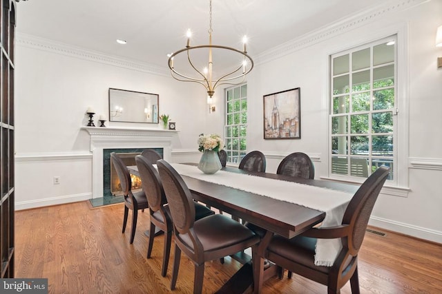  - dining space featuring a chandelier, ornamental molding, a high end fireplace, wood finished floors, and baseboards