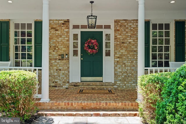  - view of exterior entry with brick siding and a porch