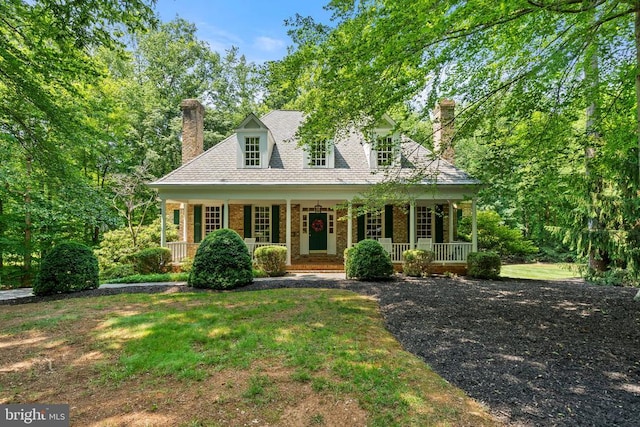  - cape cod home with a chimney, a porch, a front yard, and brick siding