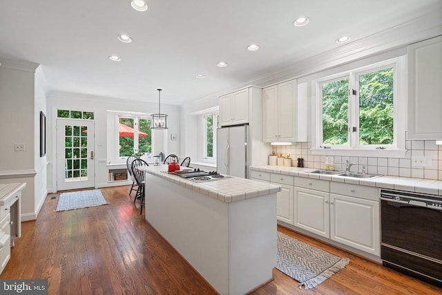  - kitchen featuring dishwasher, tile countertops, a sink, white refrigerator, and crown molding