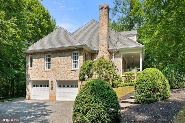  - view of front facade with an attached garage, driveway, brick siding, and a chimney