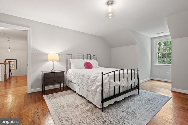  - bedroom with wood finished floors, baseboards, and lofted ceiling