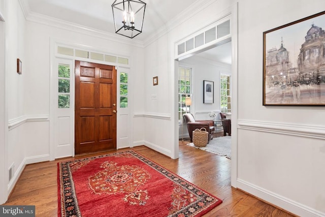  - foyer with ornamental molding, wood finished floors, a chandelier, and baseboards