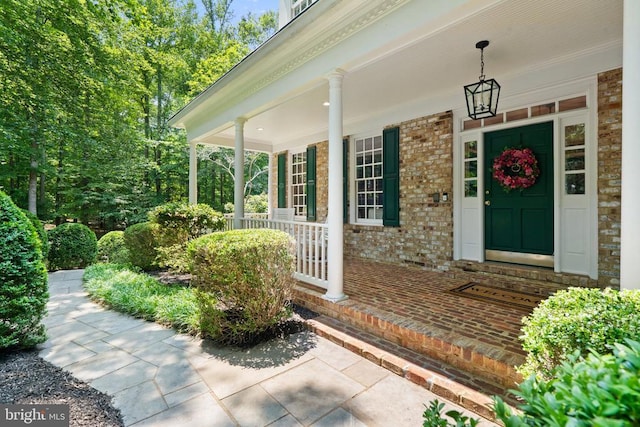  - view of exterior entry featuring brick siding and covered porch
