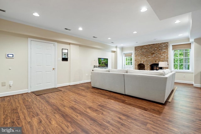  - living room with wood finished floors, baseboards, recessed lighting, ornamental molding, and a brick fireplace