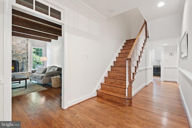  - stairs featuring wood finished floors, baseboards, and a stone fireplace