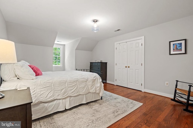  - bedroom featuring wood finished floors, baseboards, lofted ceiling, and a closet