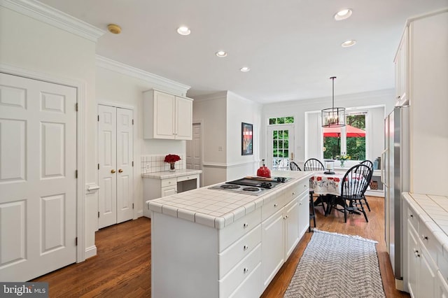  - kitchen with white electric stovetop, freestanding refrigerator, ornamental molding, a center island, and dark wood-type flooring